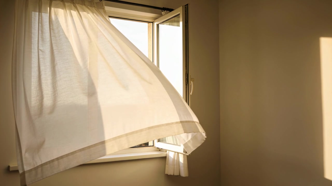 Tenda bianca trasparente che ondeggia e sventola attraverso una finestra a battente aperta, con una folata di vento che attraversa l'infisso.