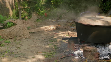 Large-iron-pot-smoking-on-open-fire-pit-with-fresh-straws-on-the-floor