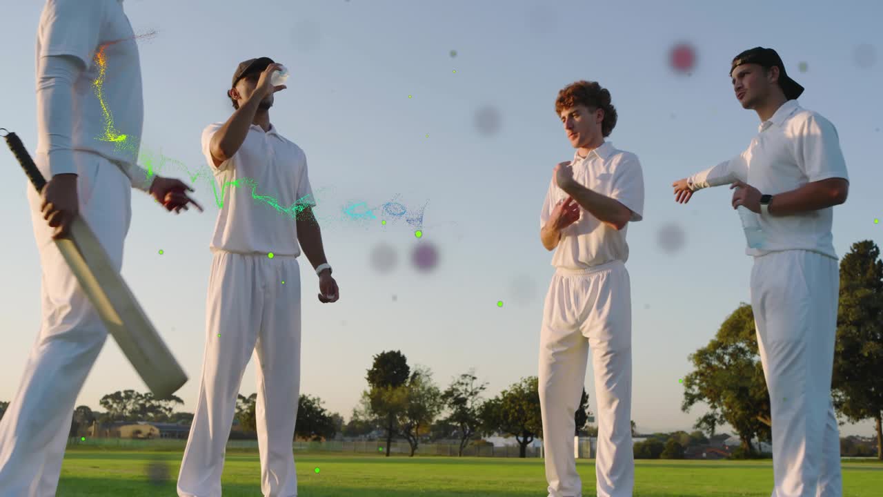 Quattro giocatori di cricket, un giocatore che prende la mazza alla fine della pausa, particelle che fluttuano sopra il gruppo con l'acqua