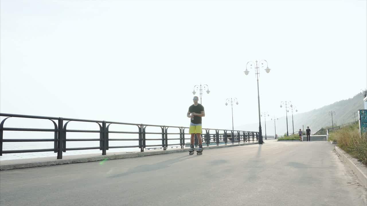 Man Rollerblading on the Coastline and Drinking Water