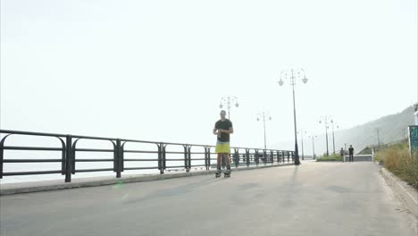 man rollerblading on the coastline and drinking water