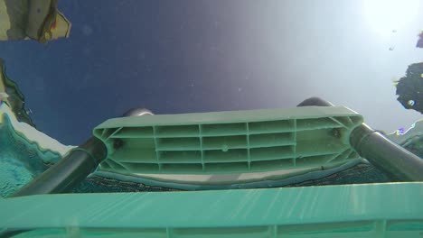 vista submarina en cámara lenta mirando hacia una escalera de piscina con burbujas provenientes de la escalera en un día soleado de verano