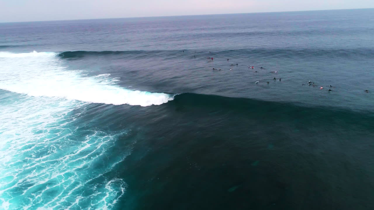 Il drone effettua una panoramica sopra un'onda tubolare e i surfisti a Cloudbreak, Fiji.