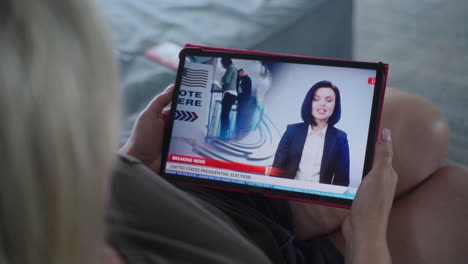 una mujer nos está viendo las noticias de las elecciones presidenciales en una tableta.