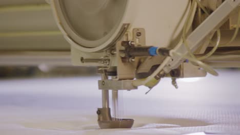 industrial sewing machine stitching fabric in a boxspring bed factory, close-up