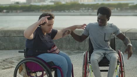 pareja feliz abrazándose y bailando usando sillas de ruedas en el muelle