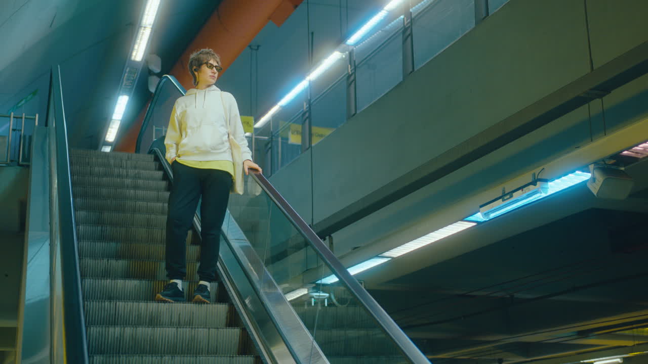 Giovane donna che scende la scala mobile in stazione della metropolitana