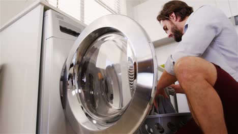 Man-putting-his-clothes-into-washing-machine