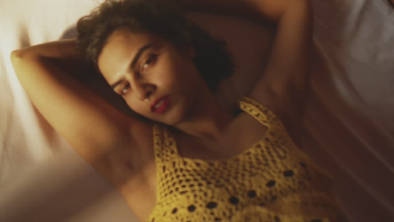 Seductive woman laying on white sheets, bedroom daydreaming blurry zoom out