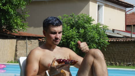 caucasian male model eating healthy cherries poolside during summer