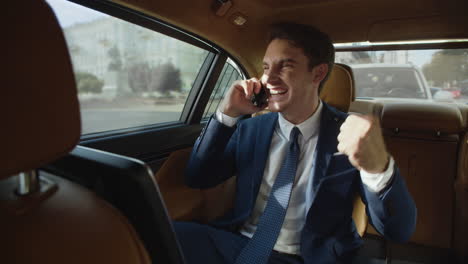 excited businessman hearing good news on mobile phone in business car.