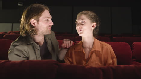 front view of couple sitting in the cinema while they talking and looking at camera