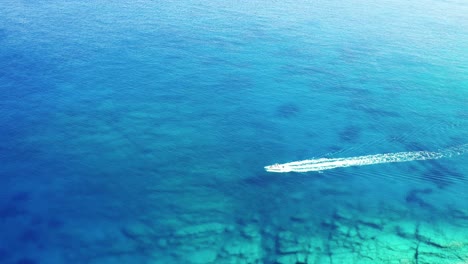 aerial drone view of boat crushing clear water in ios island greece