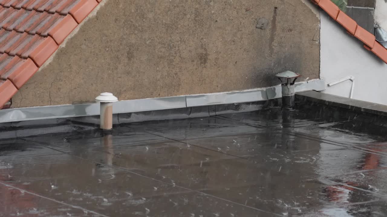 Close shot of a roof deck in a suburban neighborhood during hard rain fall