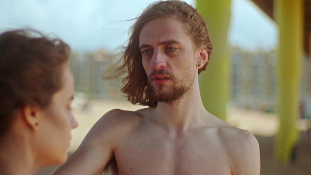 A Man Looks Shocked as He Discovers a Woman Who Has Been Abused Beneath a Pier on the Beach - Close Up