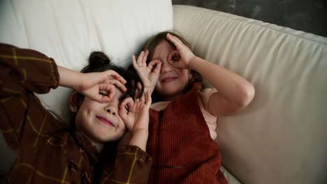 girl, friends or children on home sofa while relax together making funny faces