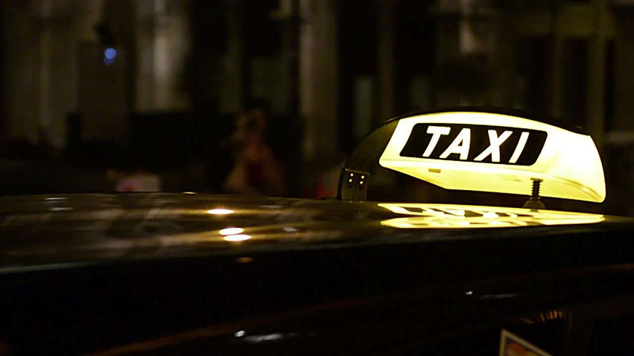 señal de iluminación de taxi que llega mientras el taxi estaciona en la ciudad por la noche