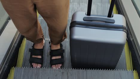 hombre con equipaje en la escalera mecánica