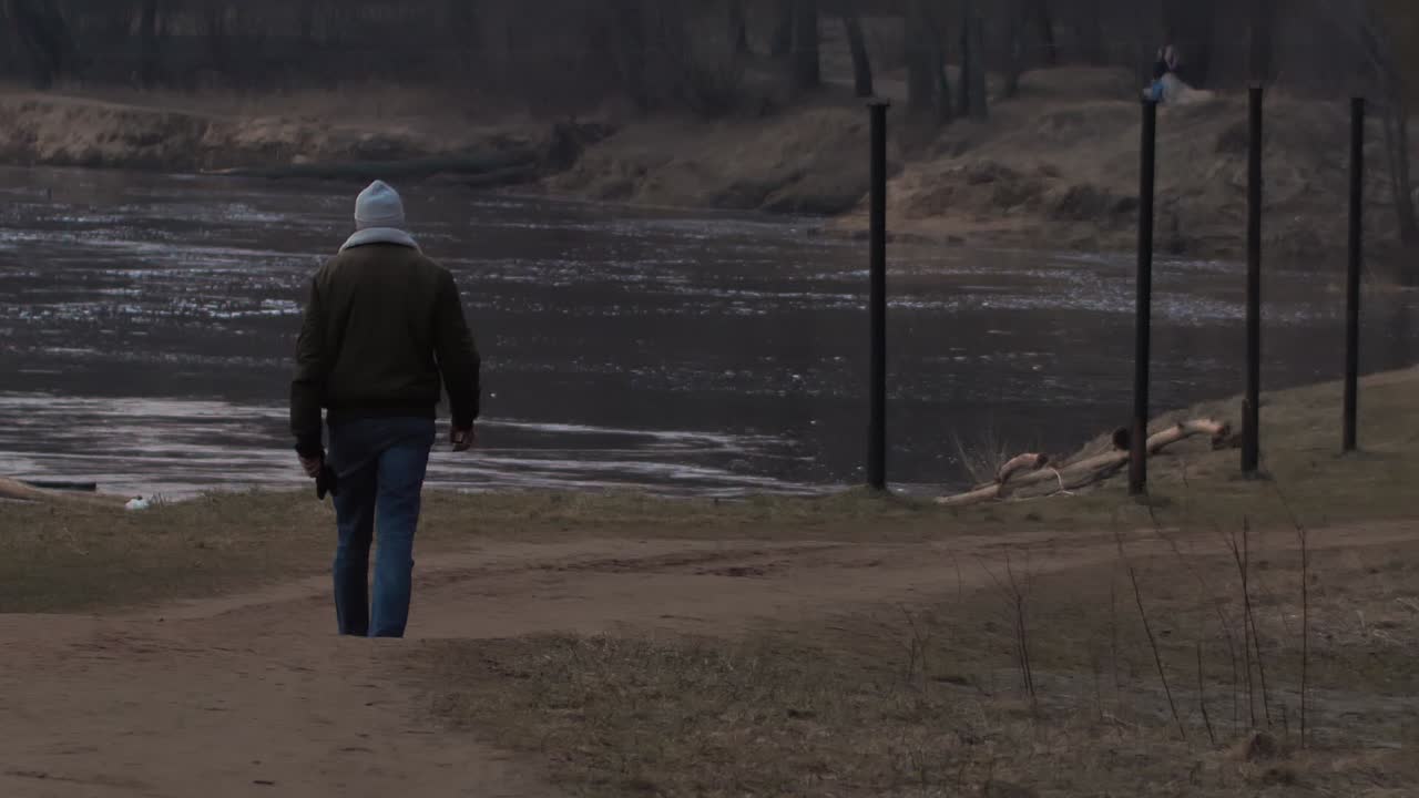 Un uomo camminava lungo la riva del fiume al tramonto.