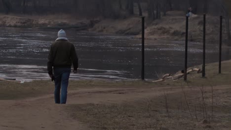 Man-was-walking-along-the-river-bank-at-sunset