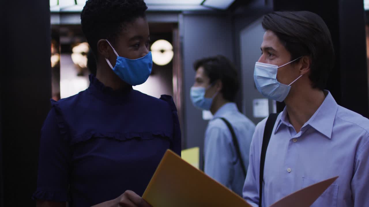 diversas personas de negocios con máscaras faciales hablando en la oficina