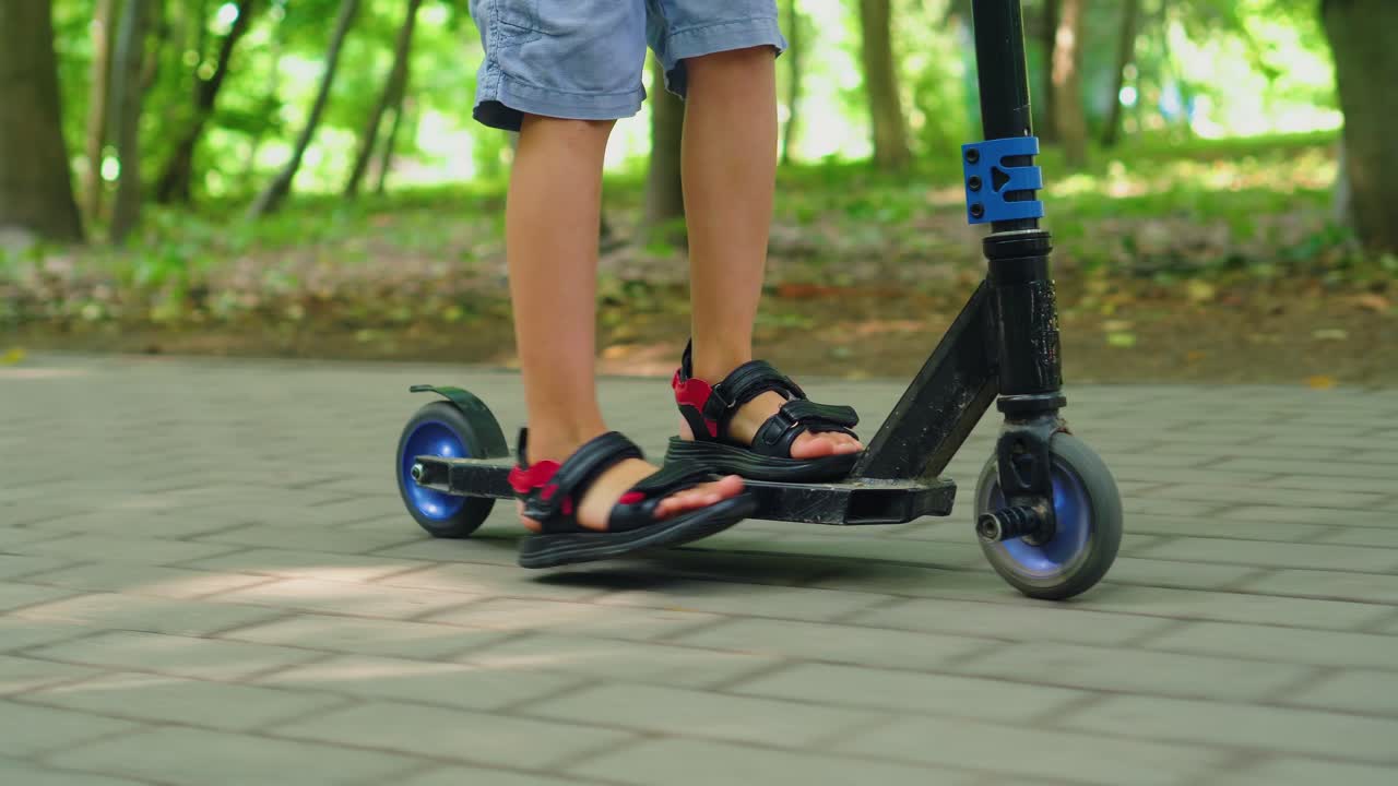 A boy rides a scooter in a city park 02