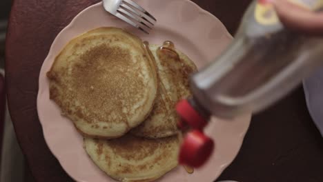 spreading maple syrup on a plate of pancakes - close up shot