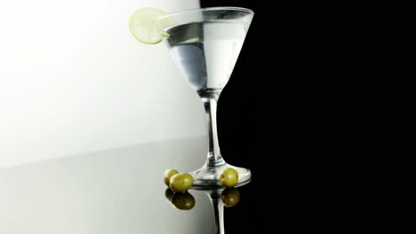 Three-olives-lying-next-to-a-cocktail-glass