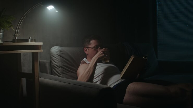 Un uomo triste legge un libro di notte in mutande