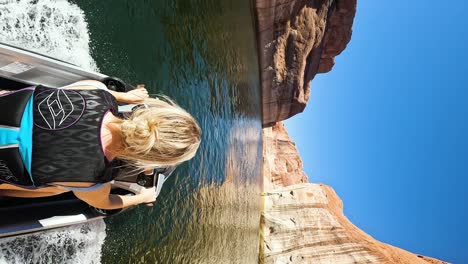 blonde hair woman drive jet ski on lake powell canyon, pov vertical shot