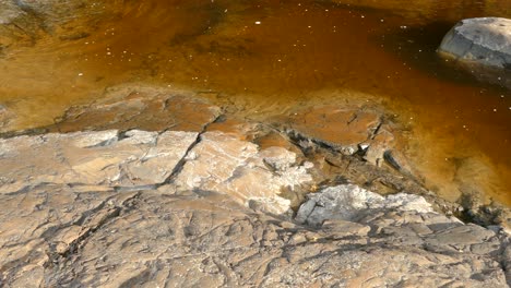 agua de color oscuro debido a la acumulación de terreno sano en rocas grandes