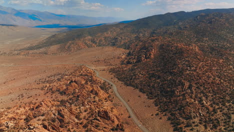 highway passing among the craggy rocks and deserted landscape. sunny day footage in the mountains of nevada from aerial view.