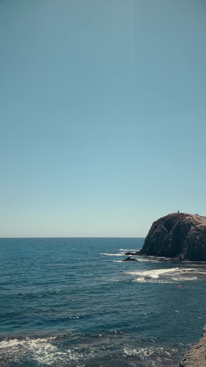 Weites blaues Meer und felsige Klippe unter klarem Himmel
