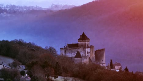 Above-of-Château-de-Castelnaud-at-sunrise-and-mist,-blue-and-pink-with-purple