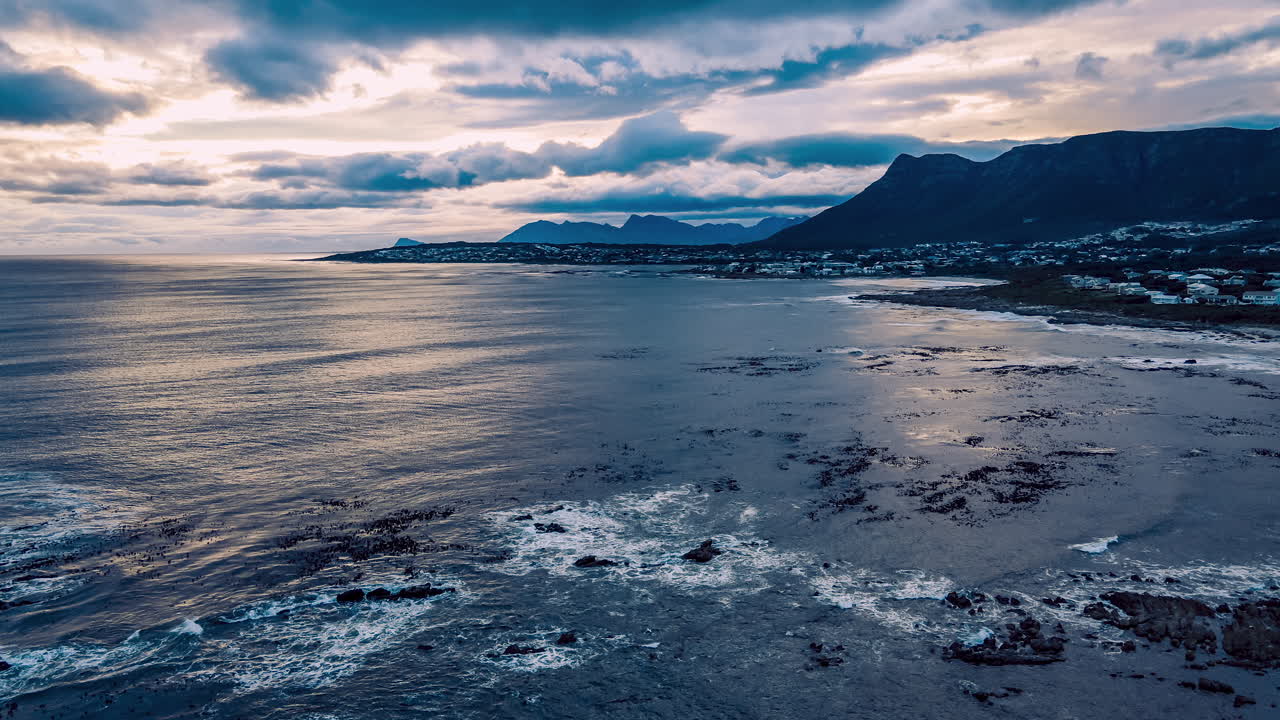 Drone hyperlapse along rocky coastline at sunset with storm clouds rolling in