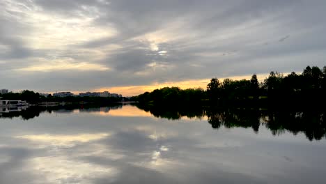 the rising sun breaks through the dark clouds over the river (4k60)