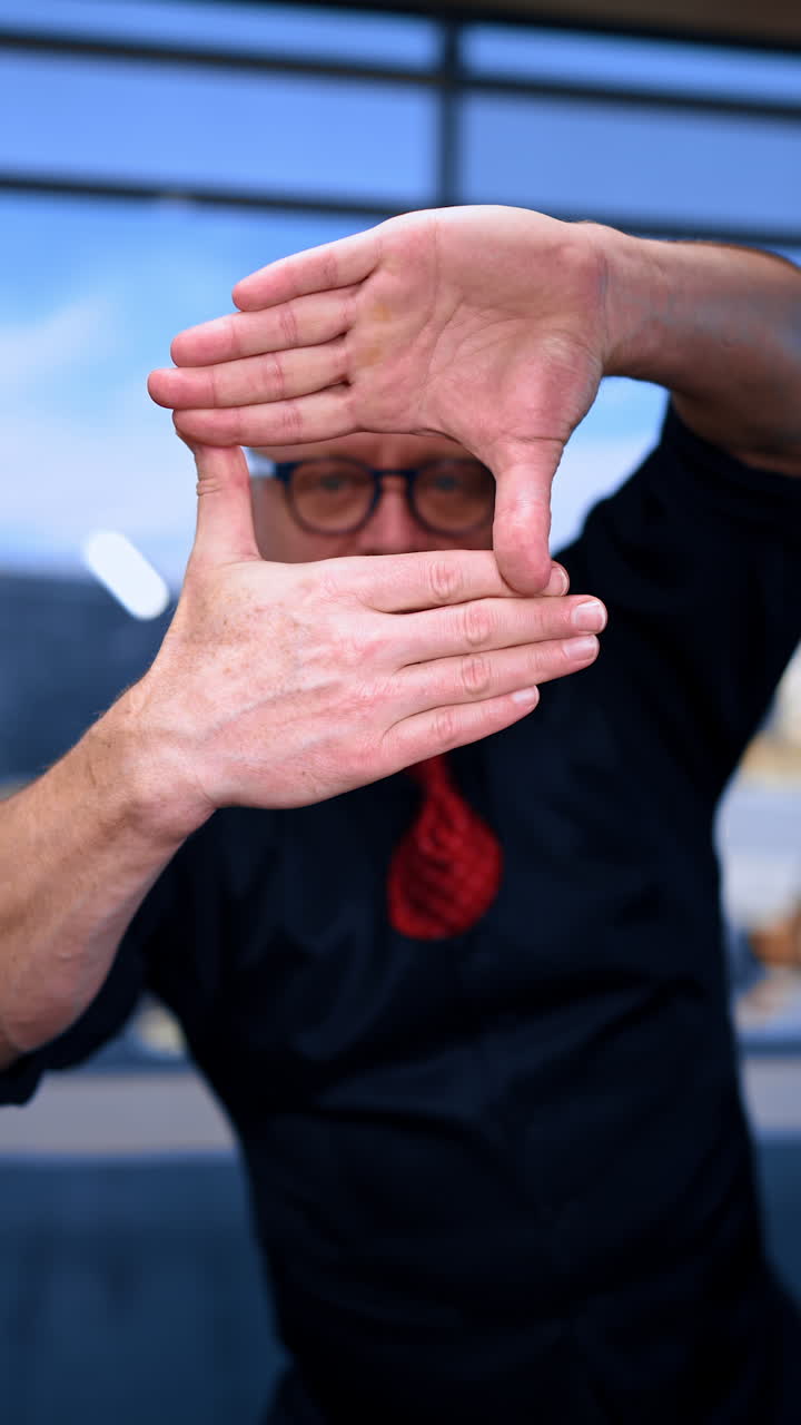 Adult male looking through the window made with his fingers. Portrait of a man peeping at you. Close up. Vertical video.