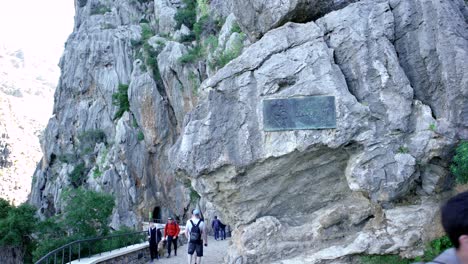 personas caminando a través de un cañón con una placa histórica