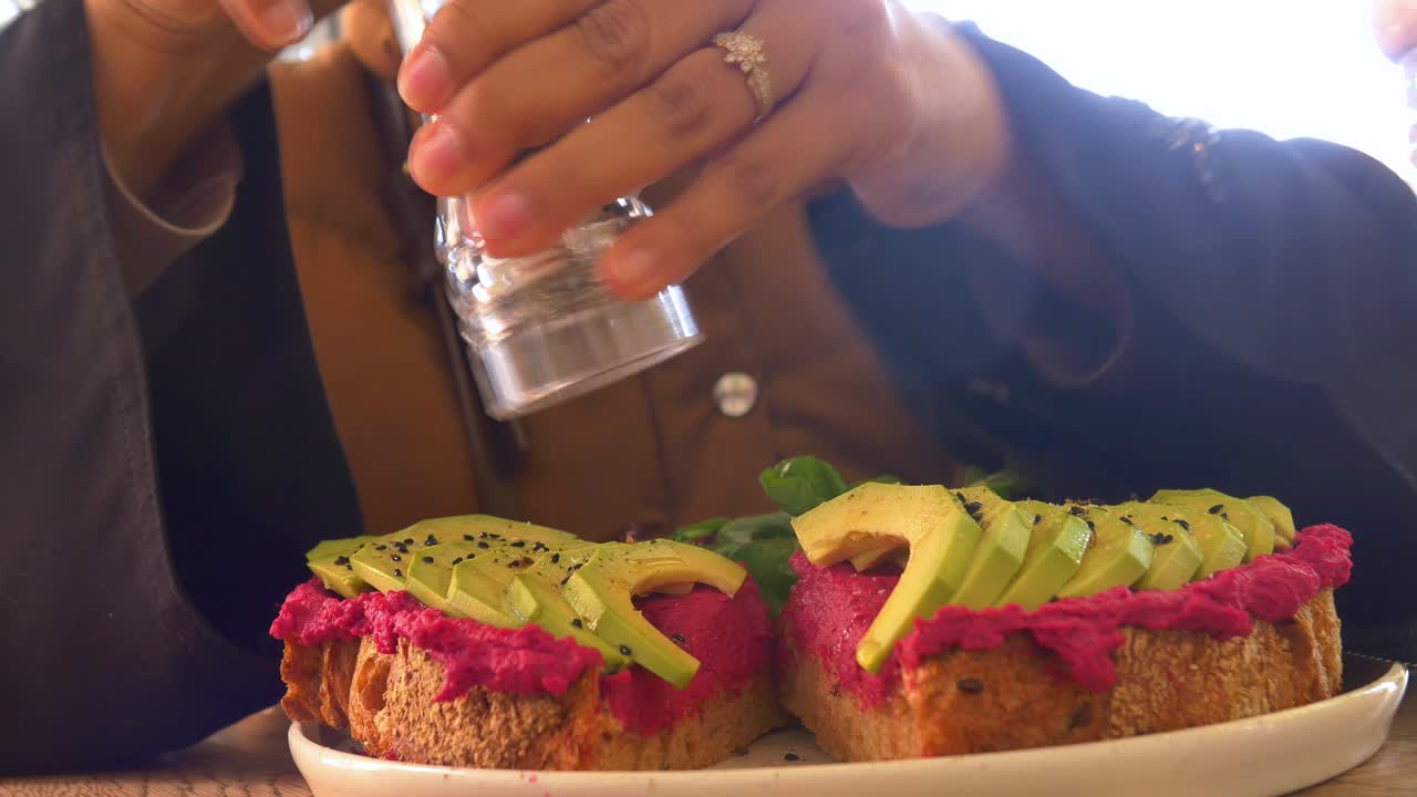 Woman enjoying a healthy avocado toast with beet hummus