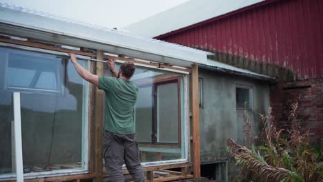 Constructor-Con-Vara-De-Metro-Plegable-Está-Midiendo-La-Holgura-De-Las-Ventanas-Del-Invernadero