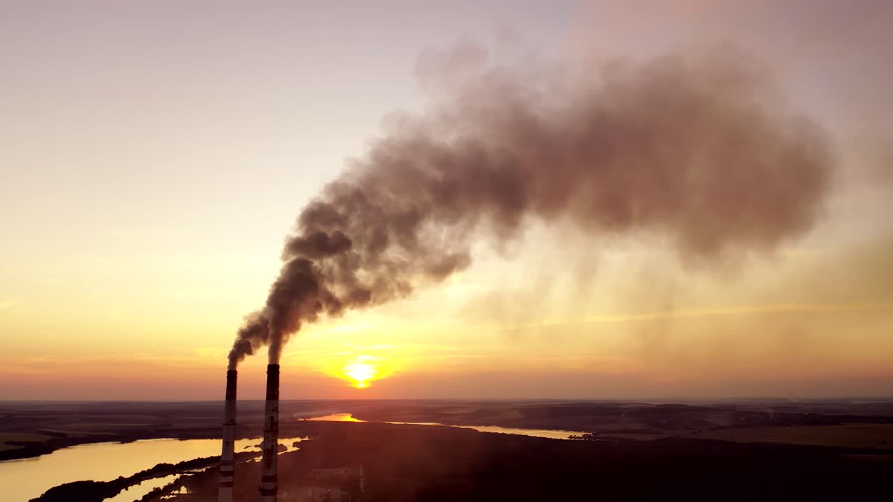 Industrial landscape. Smoke from pipes of the power plant at sunset. Environmental pollution.