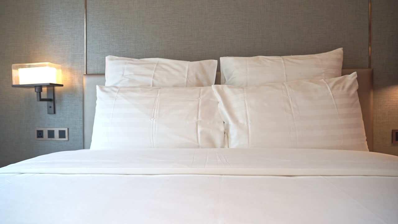 современная заправленная кровать размера king-size с 4 подушками и ночными светильниками, прикрепленными к стене