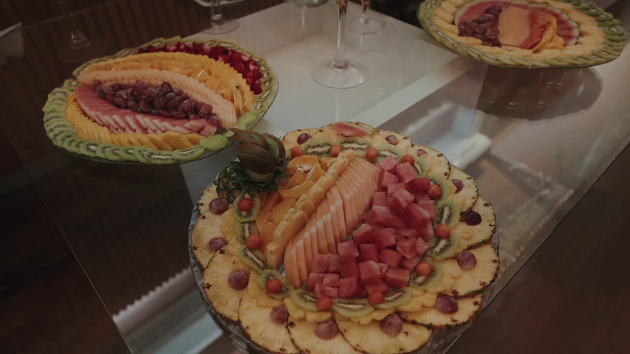 Coloridas y frescas bandejas de fruta con rodajas de piña, kiwi, melón y sandía bellamente dispuestas sobre una mesa