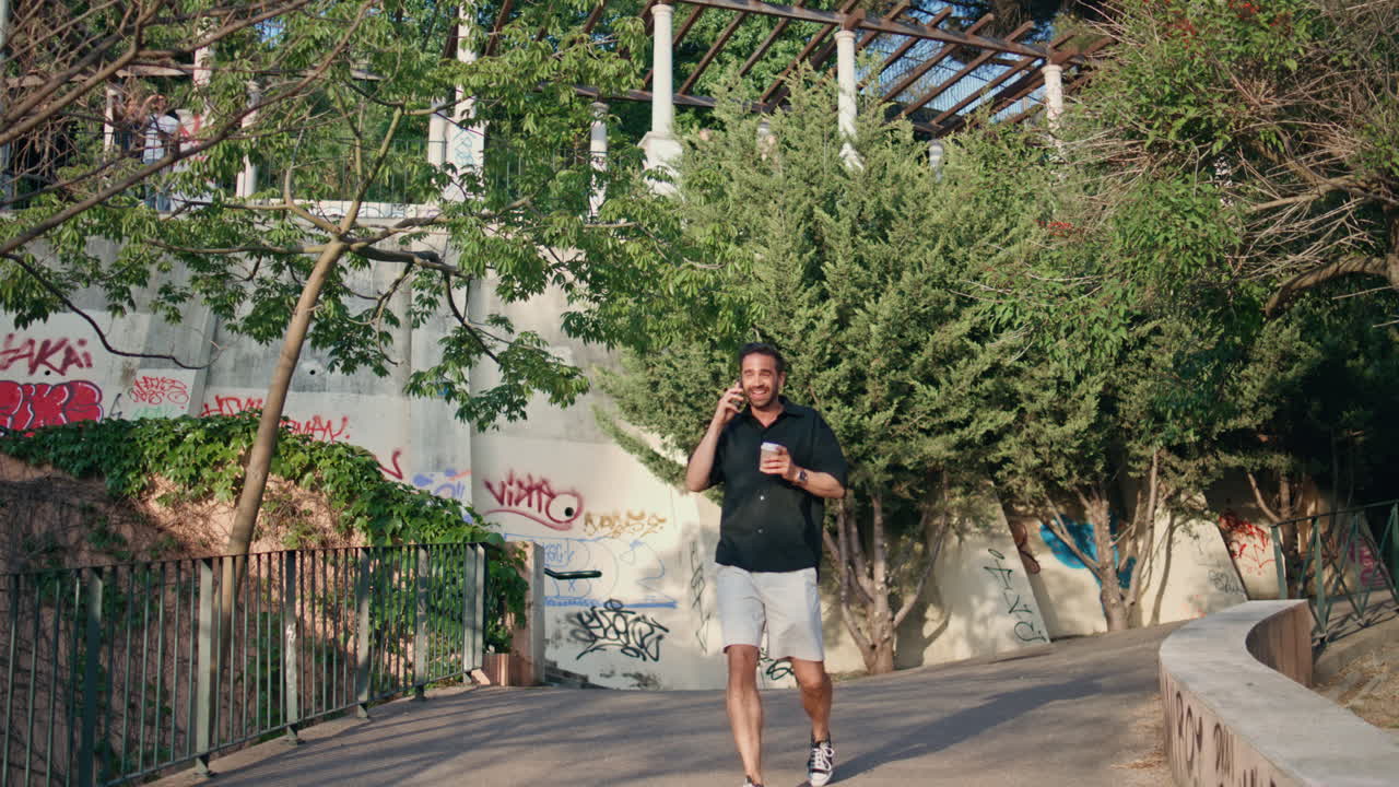 휴대전화로 전화하는 편안한 남자, 공원 골목을 는 남자, 차를 들고 웃는 남자