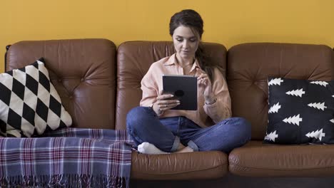 woman relaxing on a sofa with a tablet