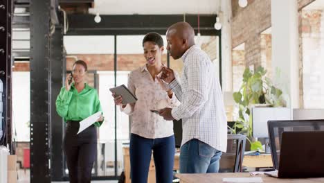 Happy-african-american-colleagues-using-tablet-and-discussing-work-in-office,-slow-motion