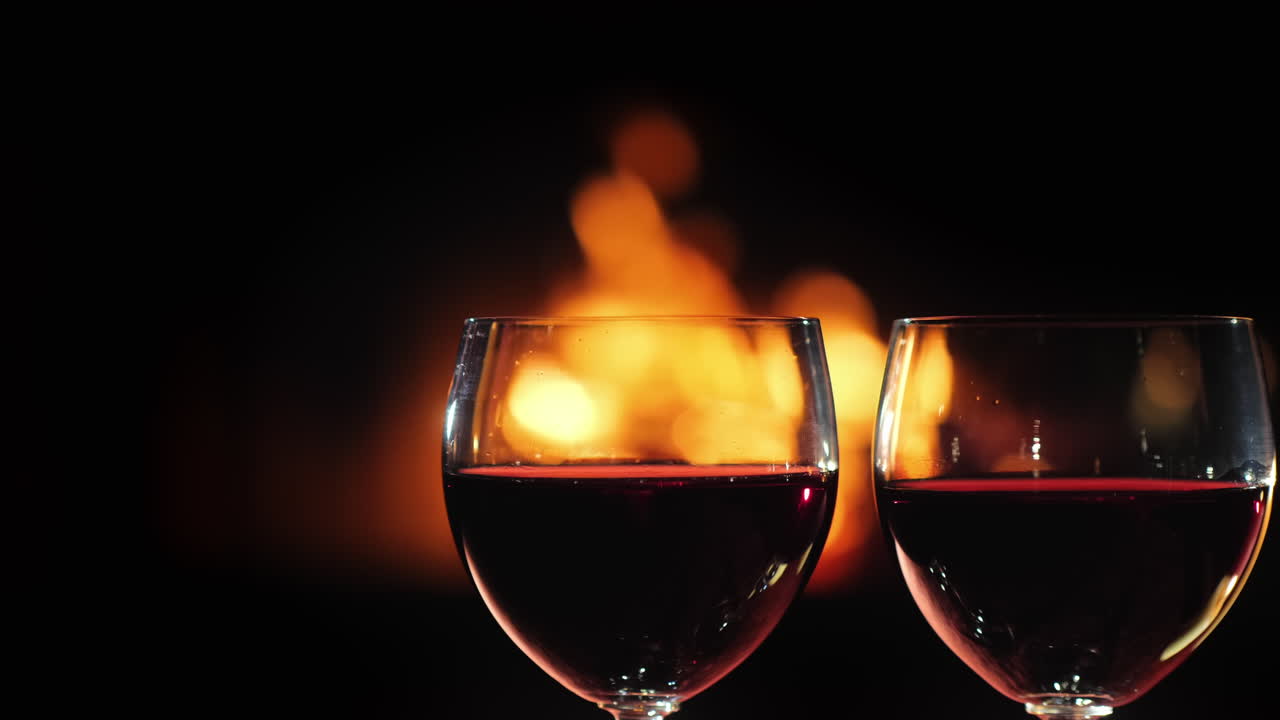 dos vasos de vino tinto contra el fondo de la chimenea donde arde el fuego
