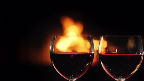 two glasses of red wine against the background of the fireplace where the fire burns