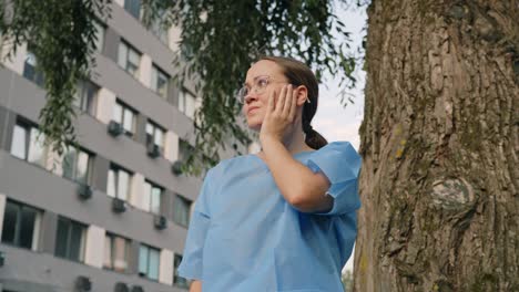 Woman-wearing-blue-coat-showing-worried-reaction-by-placing-her-hand-to-her-cheek,-static