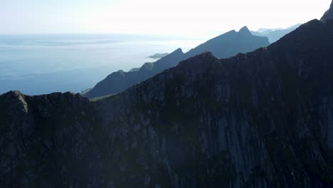 Fliegen-Entlang-Der-Kante-Eines-Berges-Mit-Blick-Auf-Die-Berge-Und-Das-Meer-Im-Hintergrund